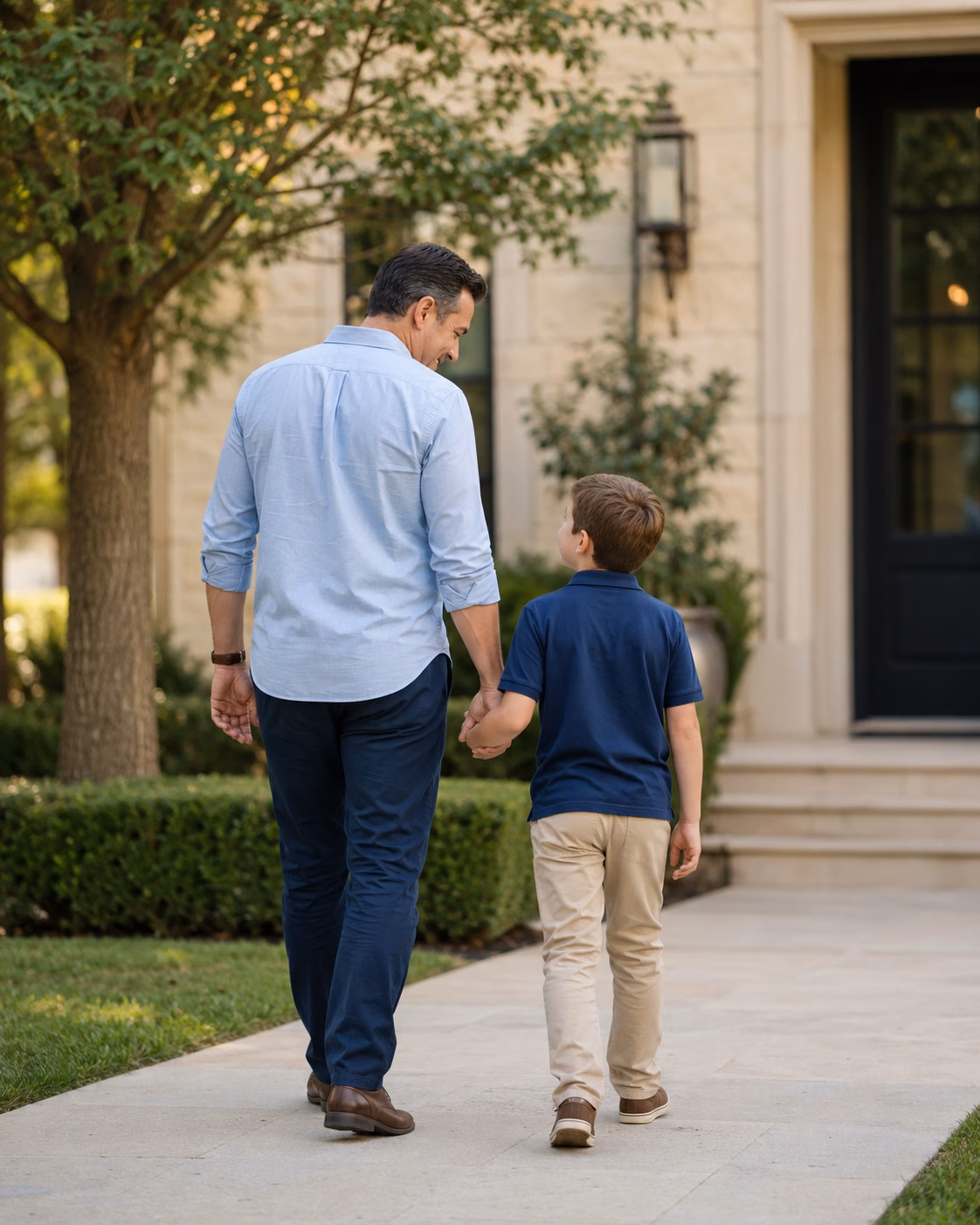 Father and child walking hand in hand outside a home